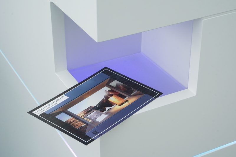 Eine Postkarte wird in die Scanner-Nische des Multitouch-Tisches gehalten