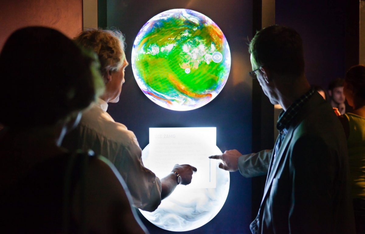 Ausstellung über die ESA im Ars Electronica Center - Besucher interagieren mit interaktiver Weltkugel