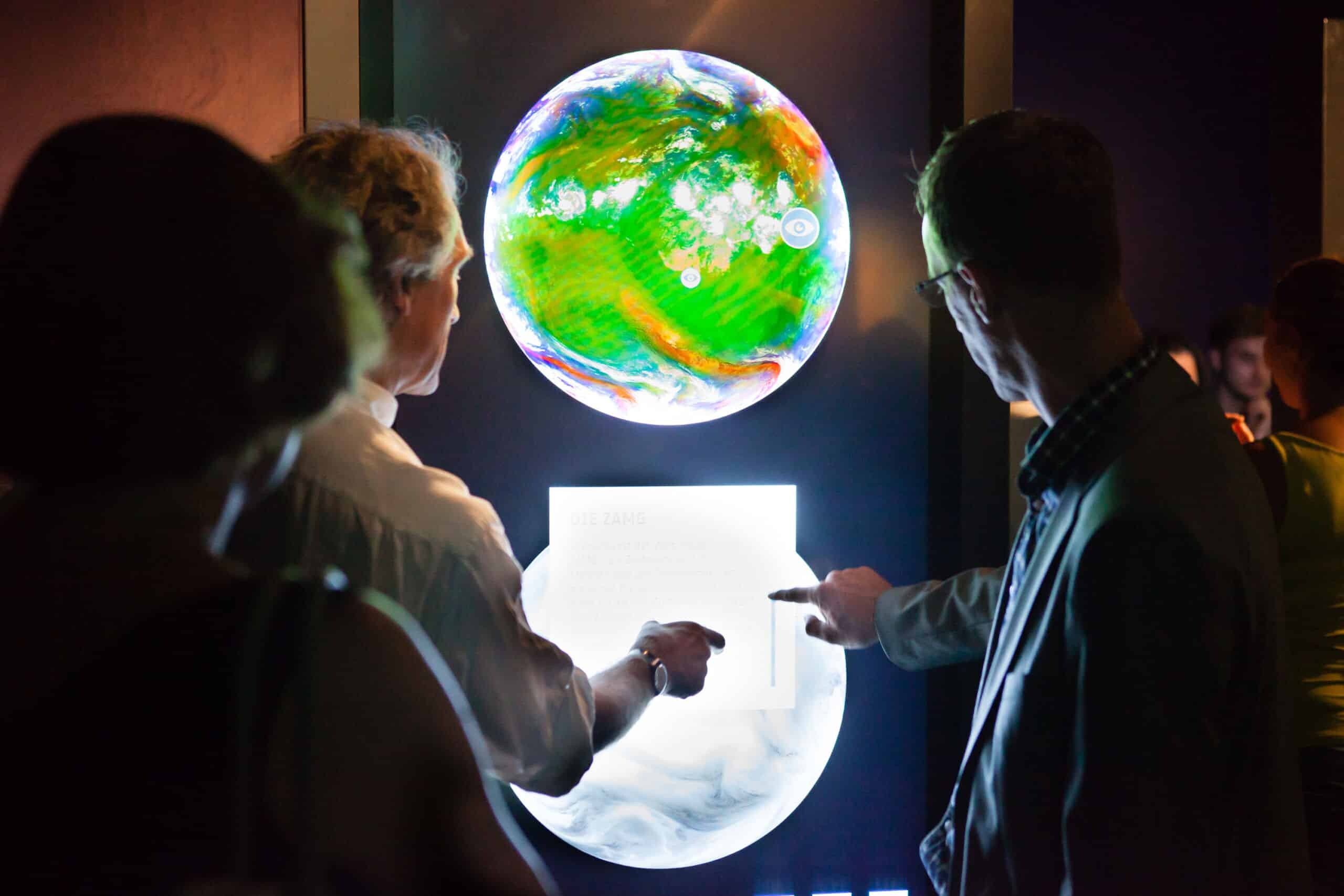 Ausstellung über die ESA im Ars Electronica Center - Besucher interagieren mit interaktiver Weltkugel