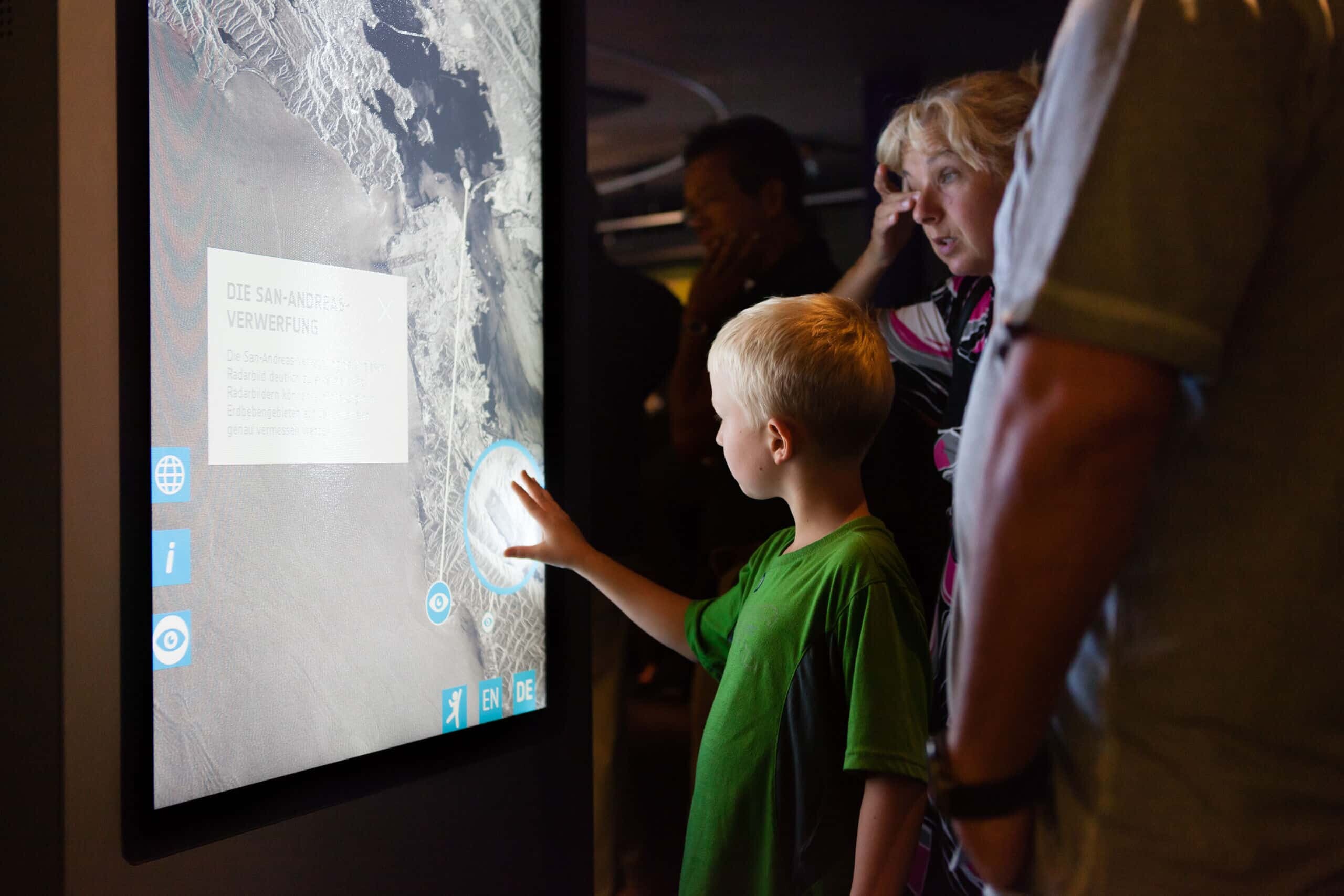 Kind berührt Multitouch-Screen einer Multitouch-Stele der Ausstellung
