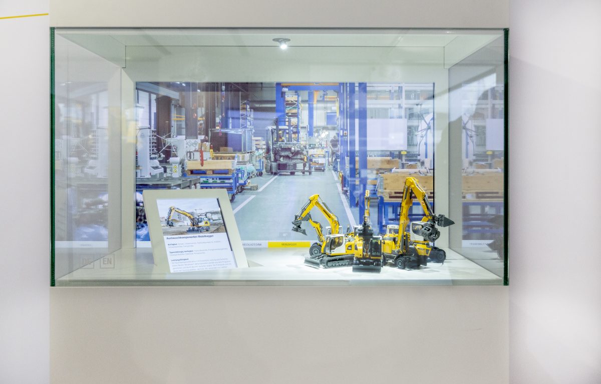 Select excavator by swiping gesture on the showcase glass and receive information on two monitors